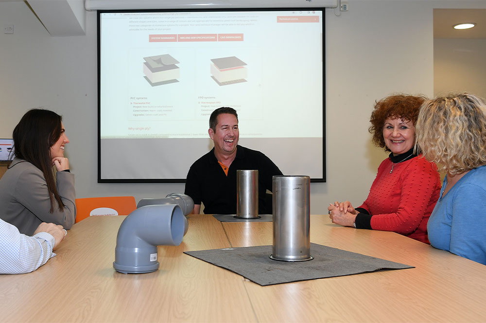 a group of people discussing bauder products laid on a table