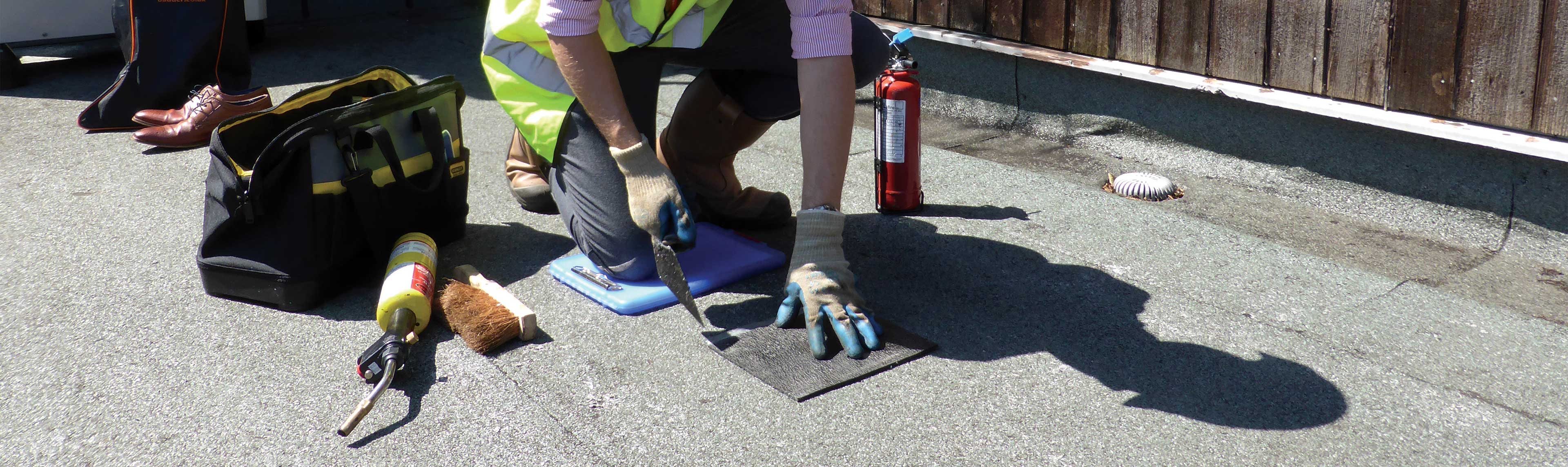 Technician with gloves core sampling a flat roof