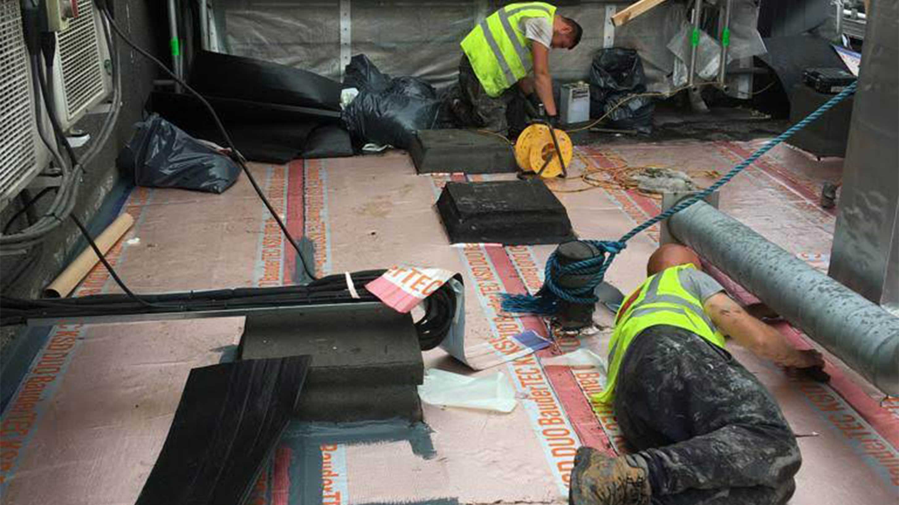 2 men working together to install Bauder roofing products on roof
