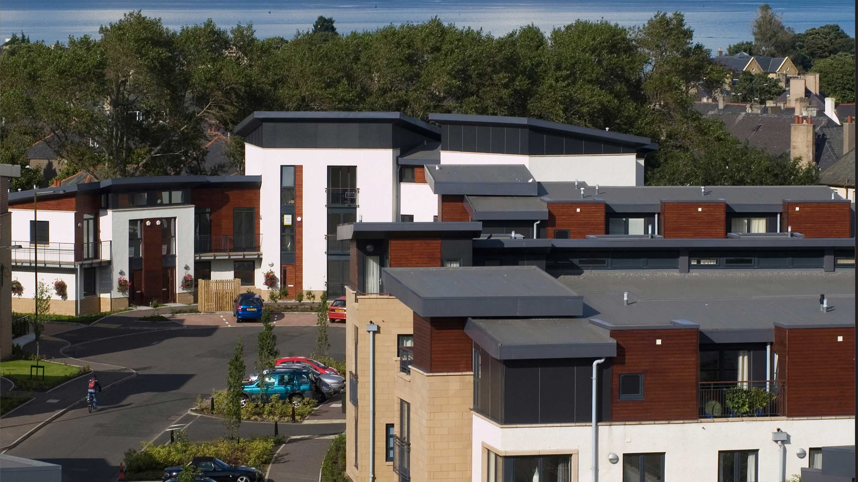 Cyclist riding through Modern housing development with cars parked