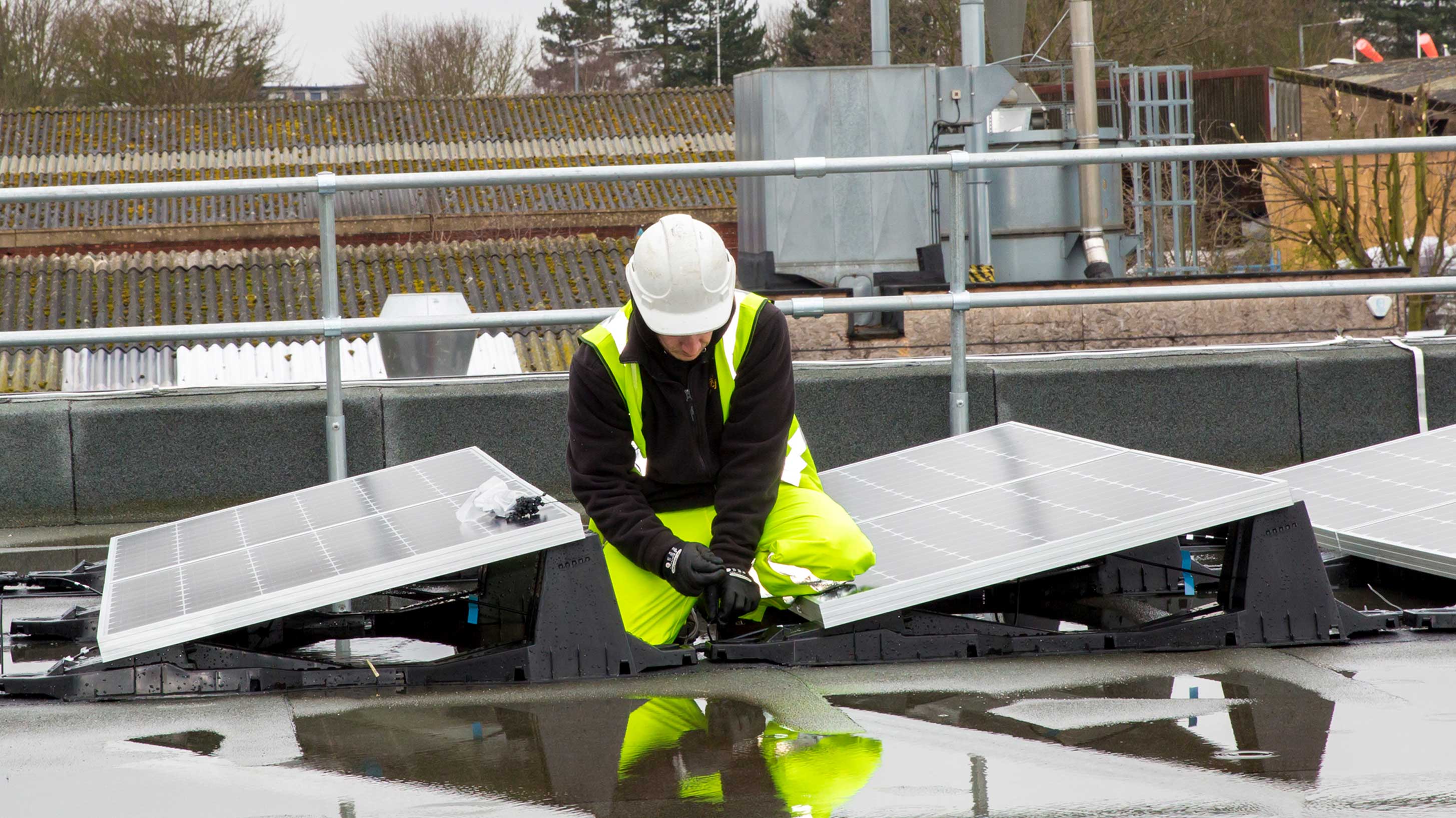 Man on rooftop adjusting solar panel installation