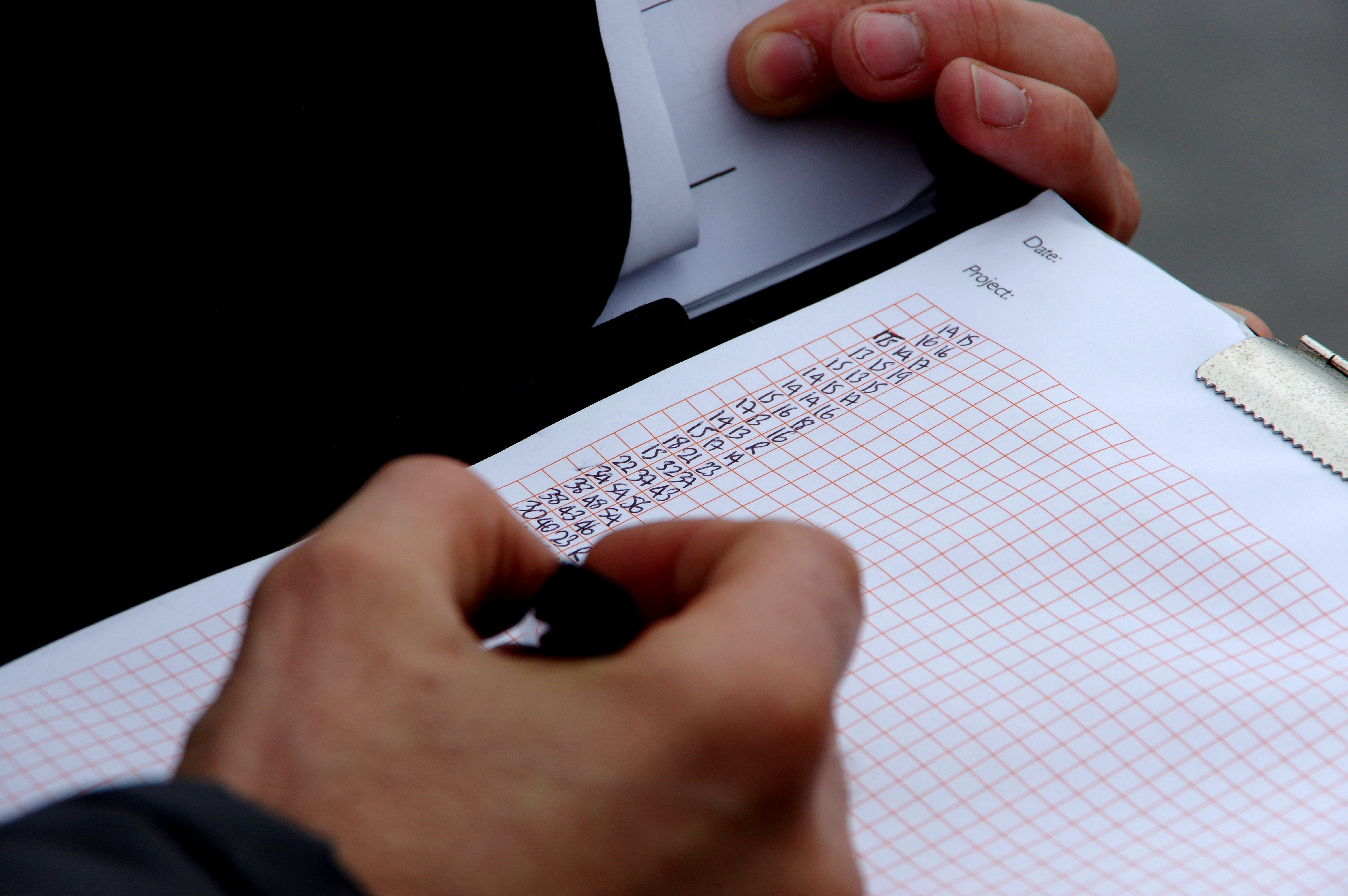 man with clipboard writing data on paper