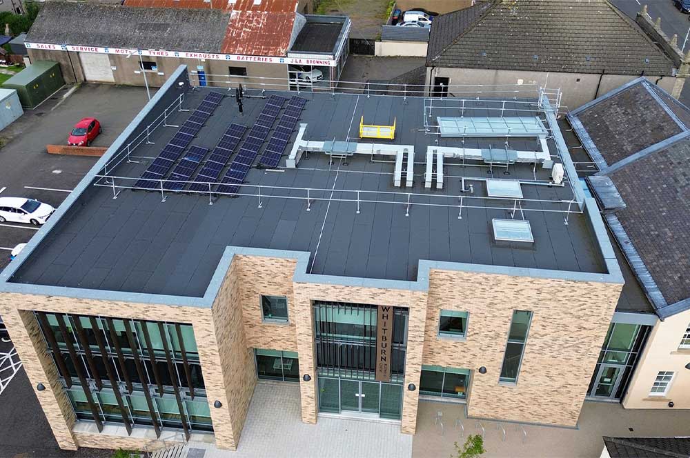Modern building, Whitburn Partnership Centre, rooftop shown with array of solar panels on Bauder total roof system with rooflights