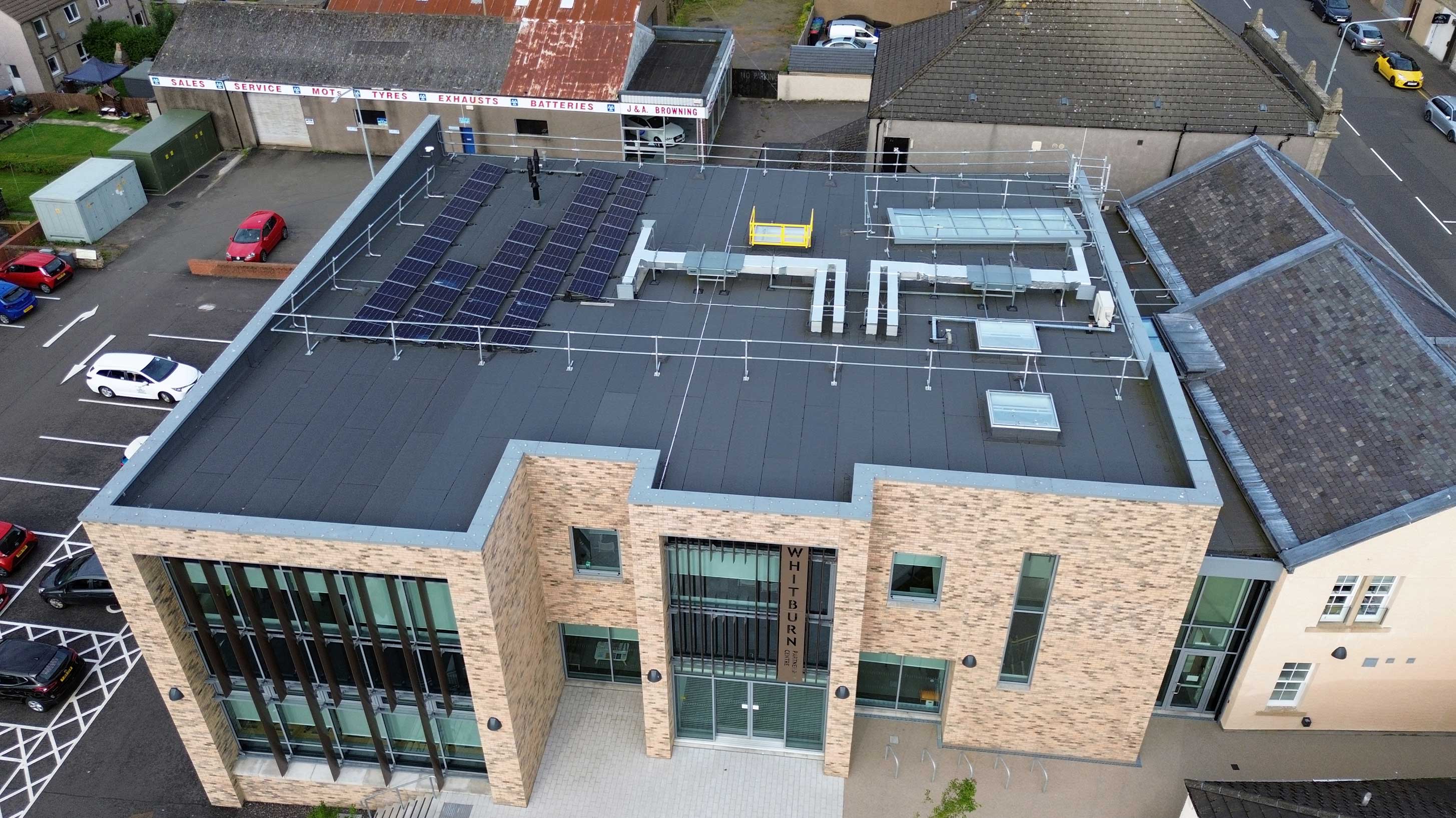 Modern building, Whitburn Partnership Centre, rooftop shown with array of solar panels on Bauder total roof system