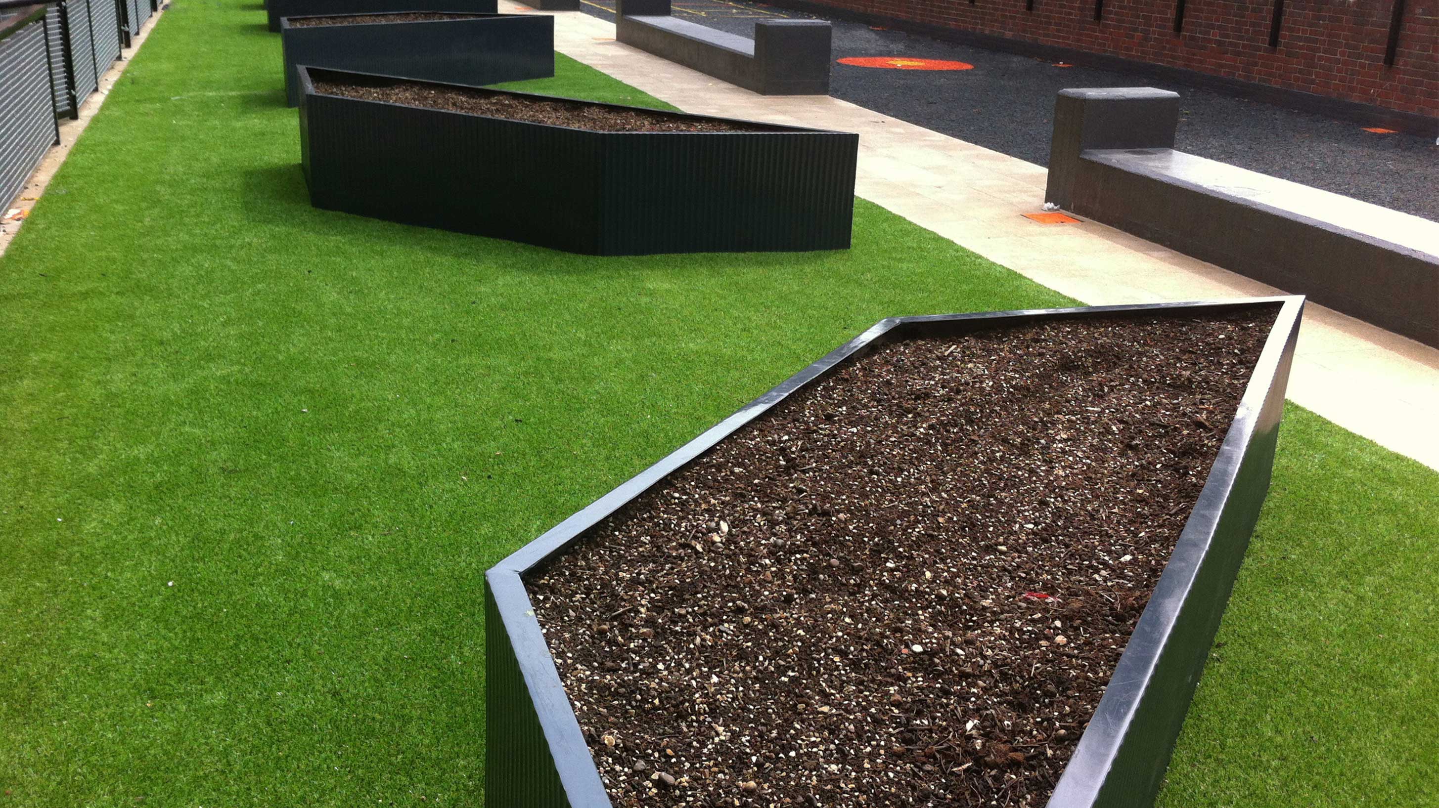 Artificial turf featuring fibreglass planters to serve as a communal garden and rubber mulch to create a play area for children