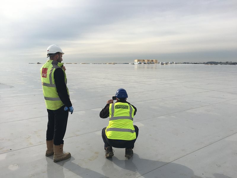 two workers inspecting roof work