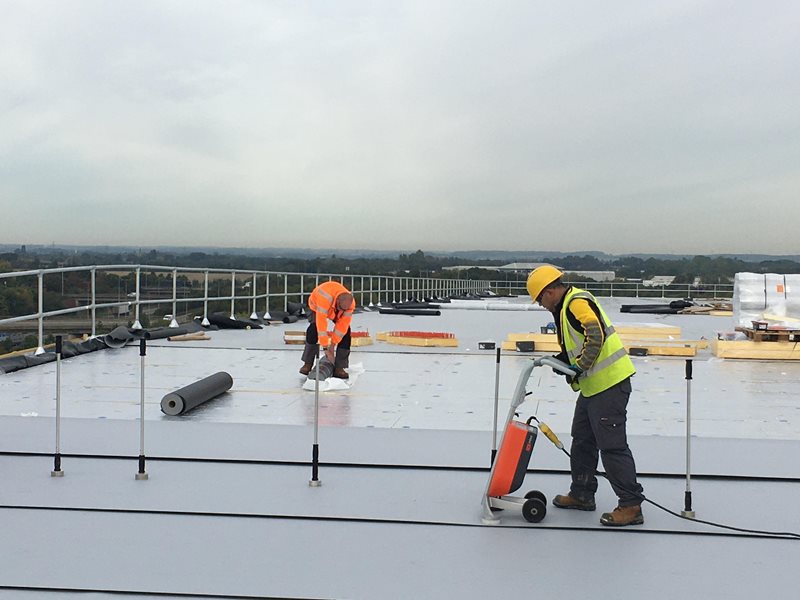 worker applies coating to roof